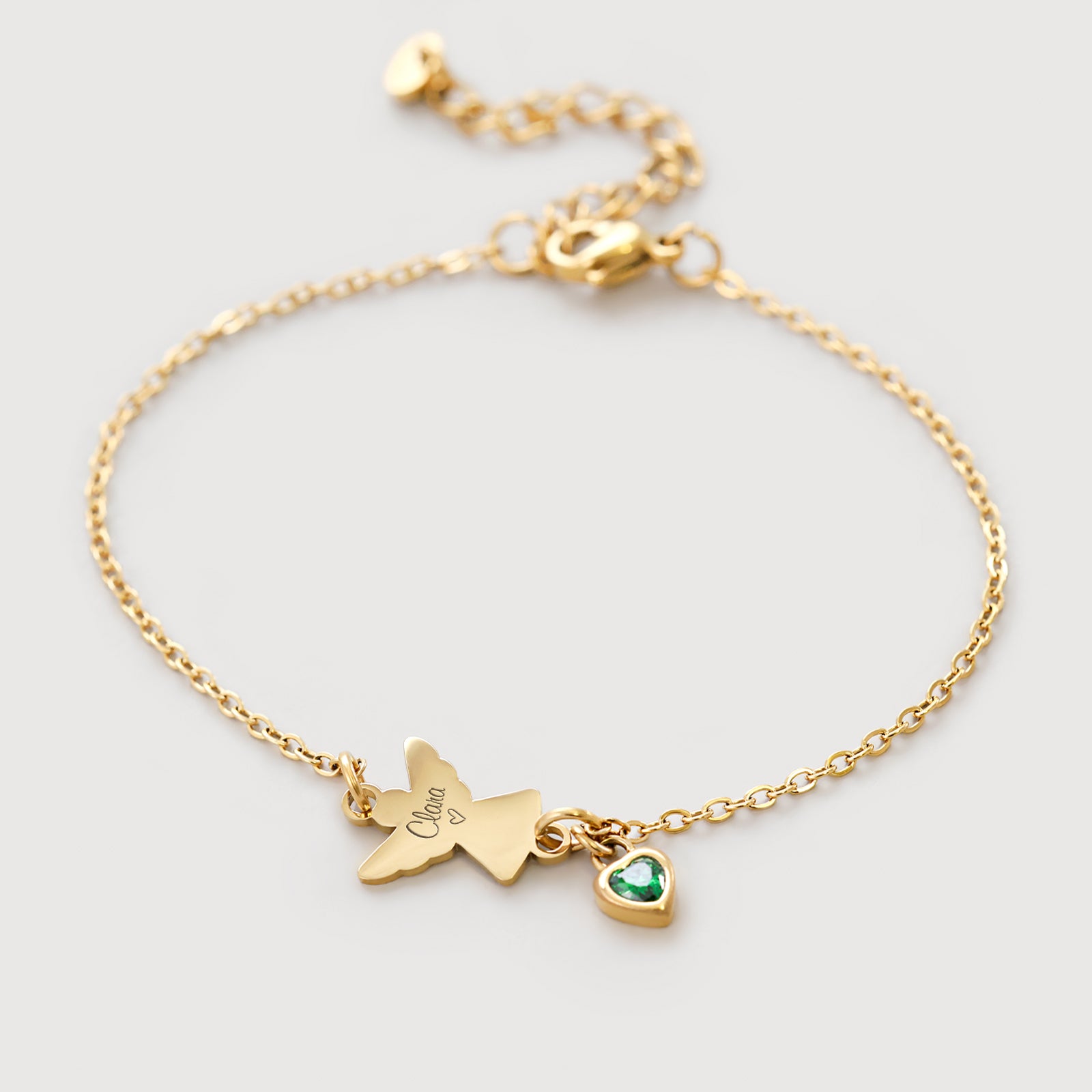 Engel Armband mit Zirkonia Geburtsstein in Gold – Flatlay mit graviertem Engelsanhänger und grünem Stein