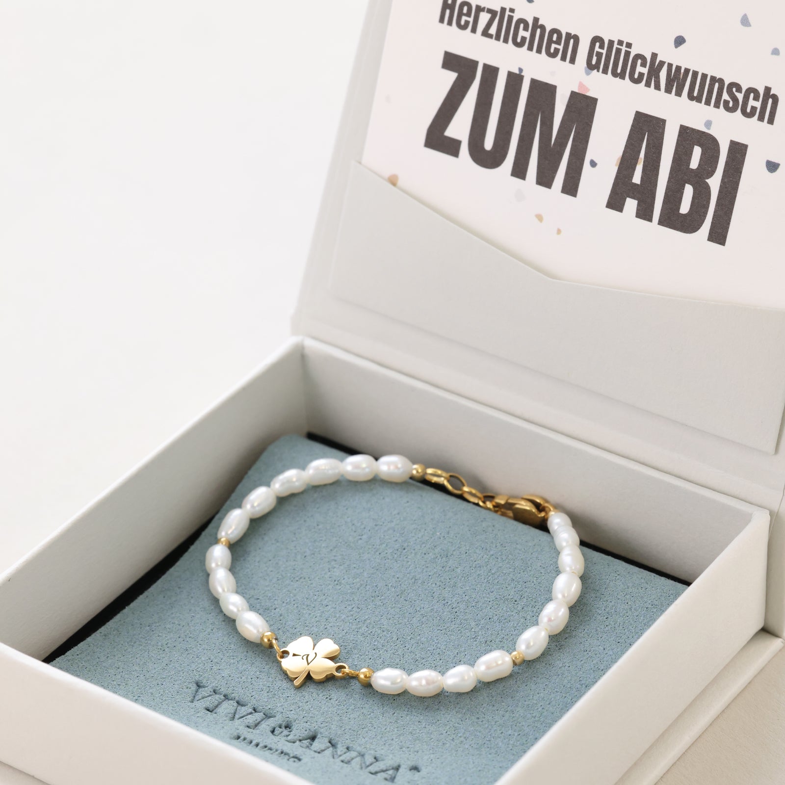 Perlenarmband mit Kleeblatt-Anhänger in offener Geschenkbox mit Abitur-Karte, Nahaufnahme