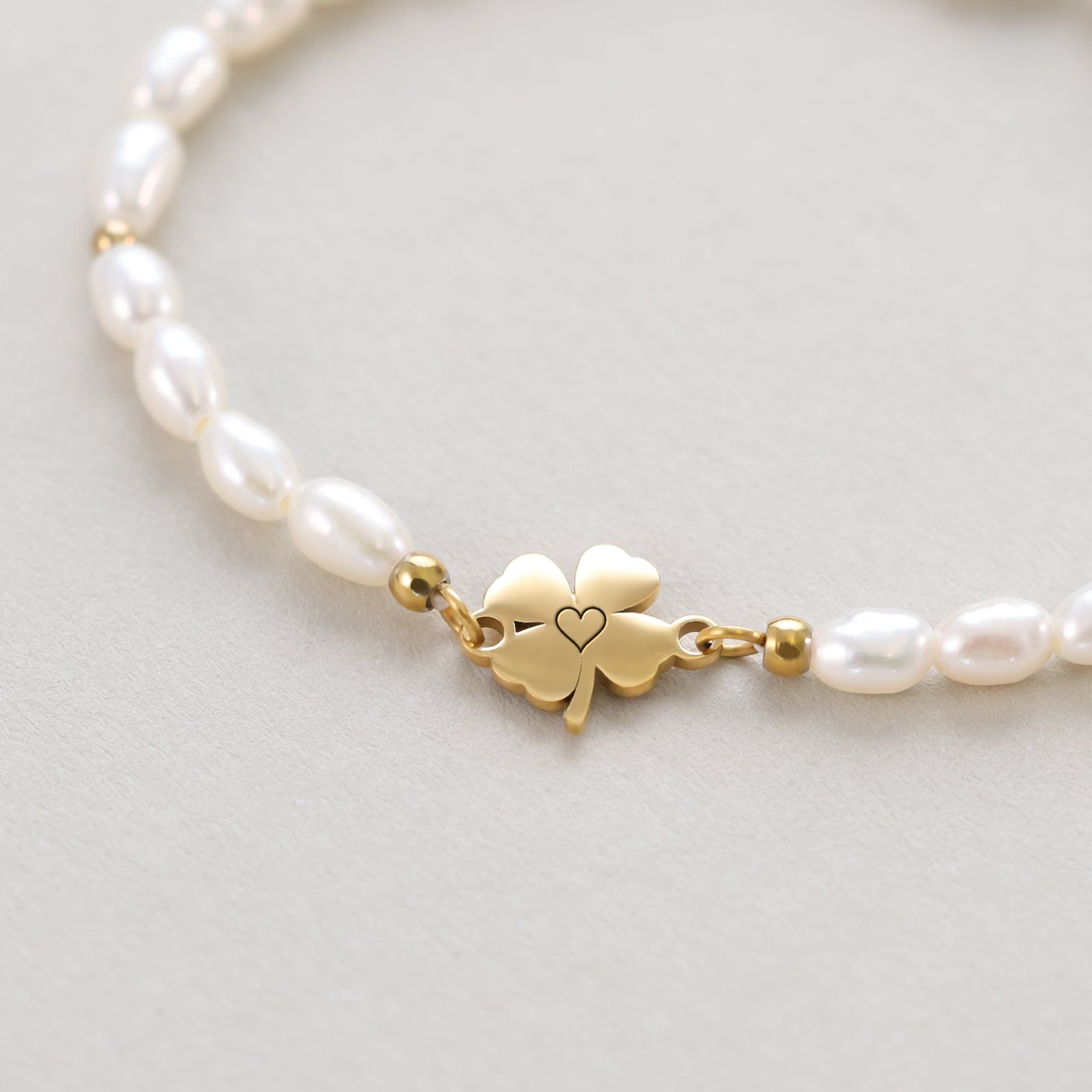 Kleeblatt Perlenarmband – Nahaufnahme des goldenen Kleeblatt-Anhängers mit Herz-Ausschnitt