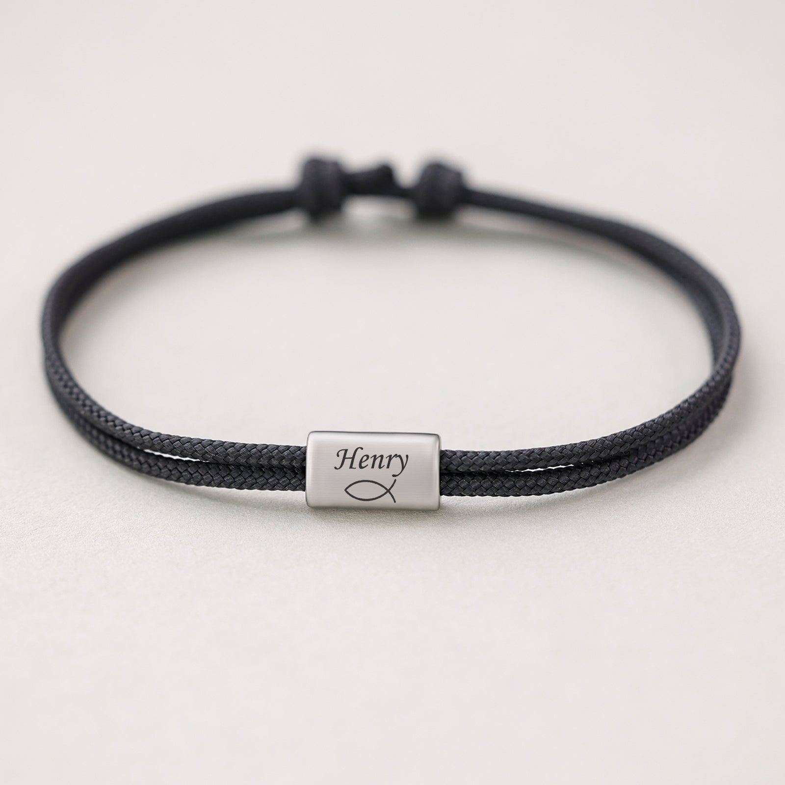 Segeltau Armband mit Gravur in Schwarz, einzelnes Plättchen mit Namen und Fisch-Symbol graviert