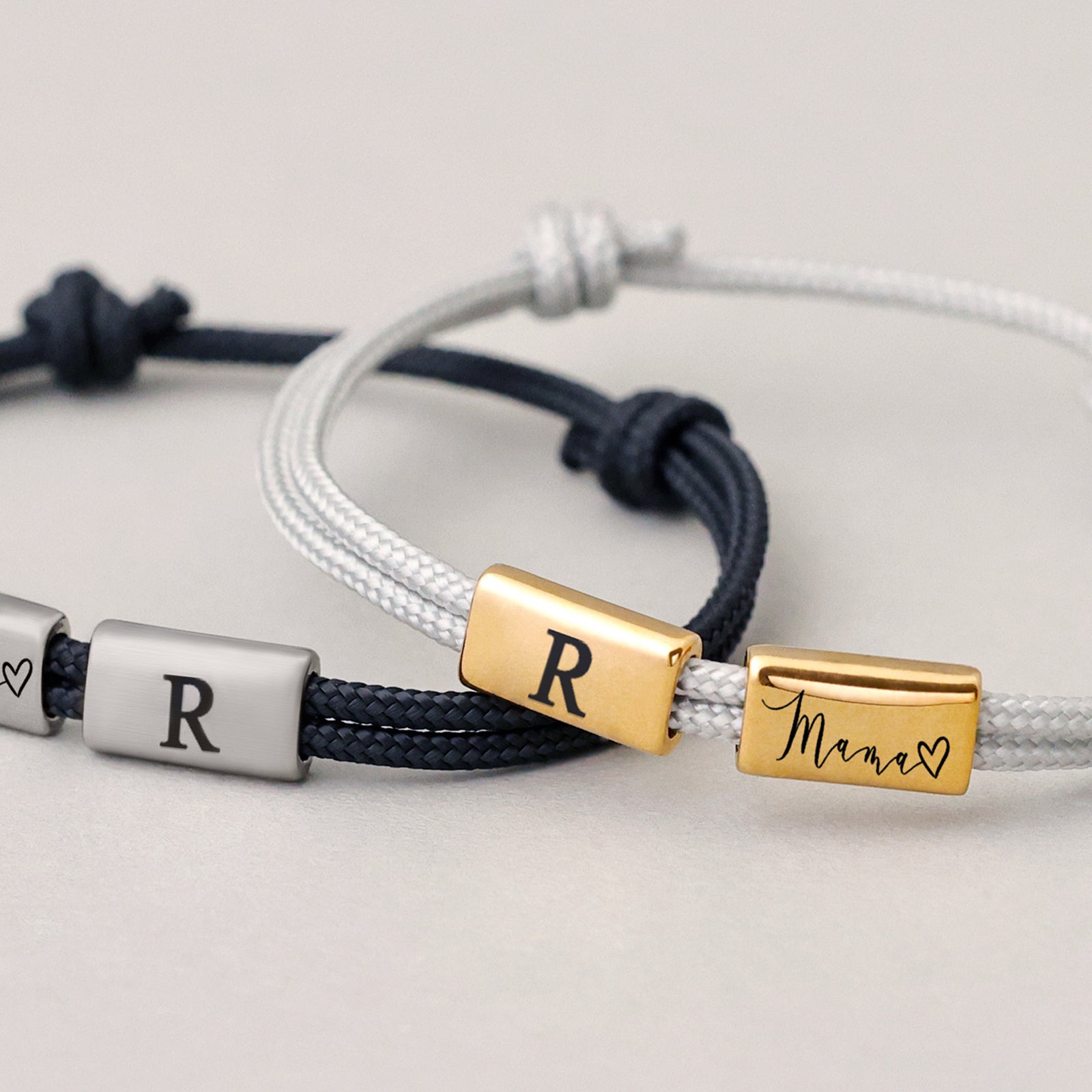 Zwei Segeltau Armbänder mit Gravurperlen – navy mit Initiale 'R' und Herz, weiß mit 'R' und 'Mama'