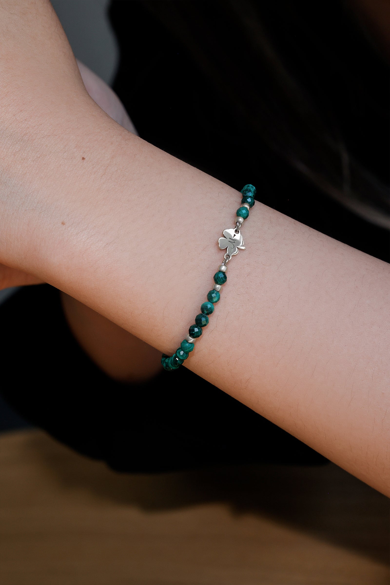 Frau trägt Malachit-Armband mit Kleeblatt in Silber – Nahaufnahme am Handgelenk