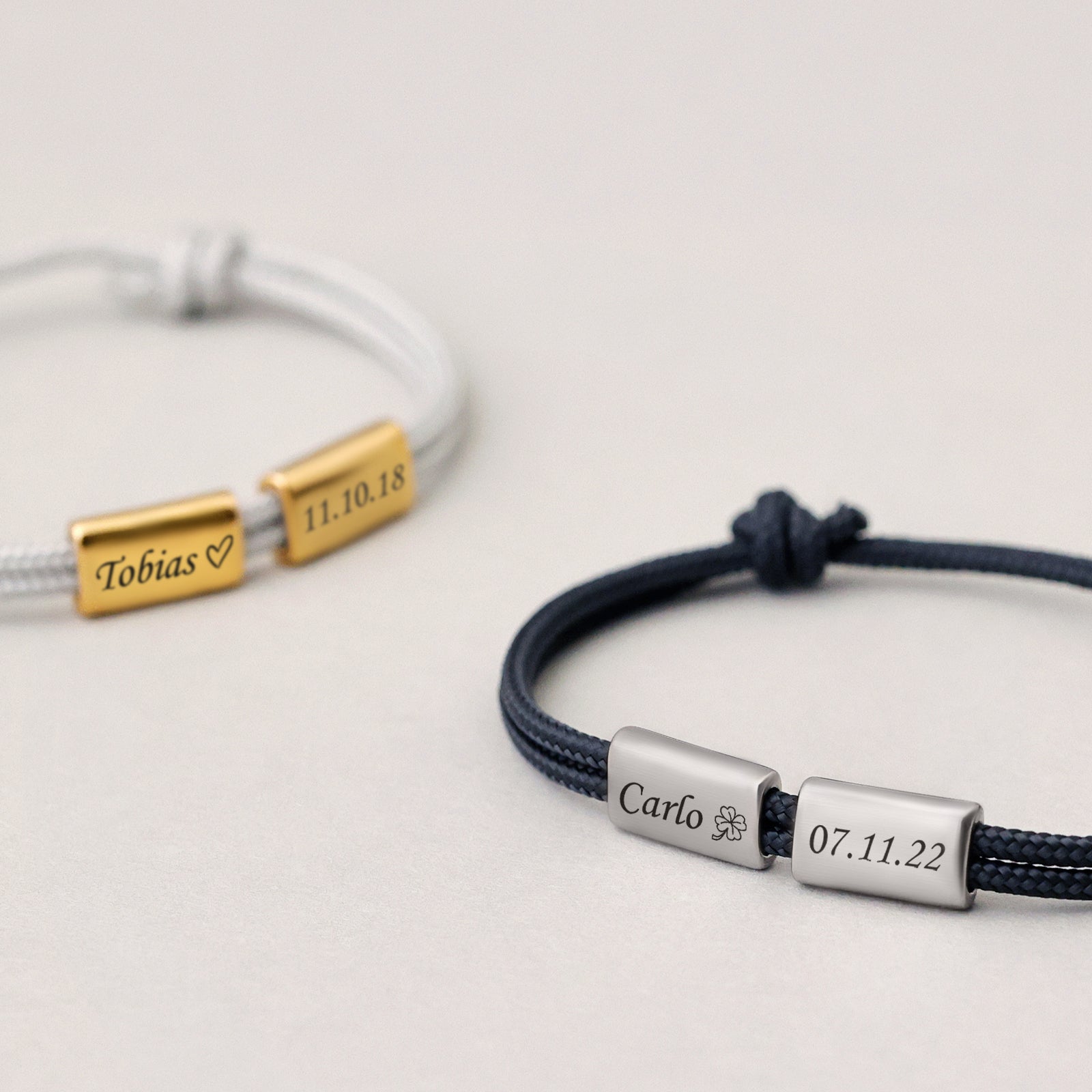 Zwei Segeltau Armbänder mit Gravurperlen – weiß mit 'Tobias' und Datum, marineblau mit 'Carlo' und Kleeblatt