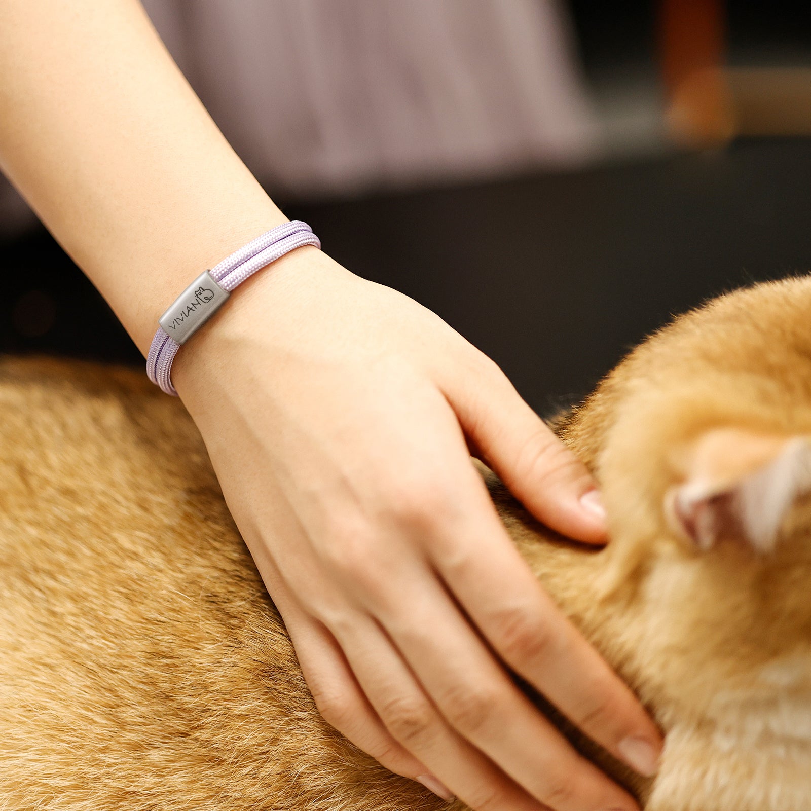 Segeltau Armband mit Gravur in Lila am Handgelenk, Plakette mit Herz-Symbol, Hand streichelt Hund